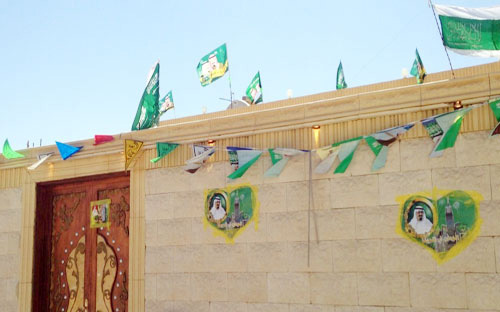 مواطنة في رفحاء تزيِّن منزلها بأعلام الوطن وصور الملك 