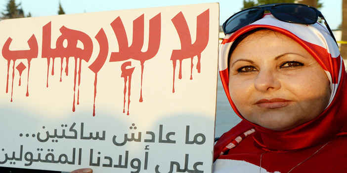  تونسية تحمل لافتة منددة بالإرهاب خلال مسيرة وطنية