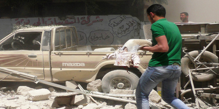  رجل يحمل جثة طفل سقط أثناء غارات النظام على إحدى القرى السورية