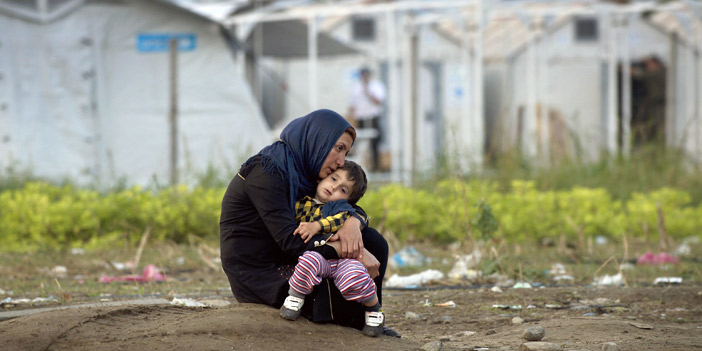  امرأة مهاجرة تحتضن طفلها بانتظار مستقبل هجرتهم