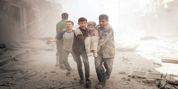  شابان سوريان يحملان طفلاً خرج من ركام أحد المباني المهدمة من جراء قصف النظام