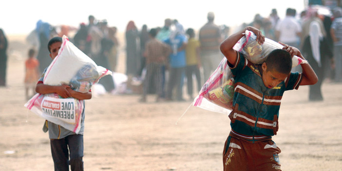  طفلان عراقيان من الفلوجة يحملان أكياس مساعدات للنازحين