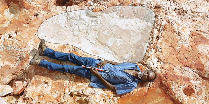  ريتشارد هنتر مستلقياً إلى جوار أكبر أثر لقدم ديناصور في العالم، وهو من سلالة الديناصورات الثيروبودية