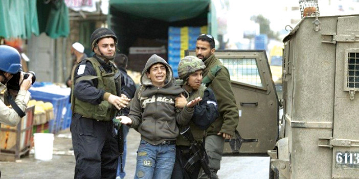  جندي من قوات الاحتلال يهم بأعتقال طفل فلسطيني