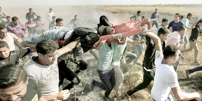  جريح فلسطيني يحمله زملاؤه بعد مواجهات مع قوات الاحتلال