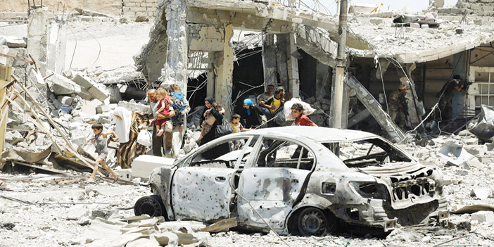  سيارة ومبانٍ مدمرة وعائلة عراقية نازحة جراء الاشتباكات بين داعش والقوات العراقية الدائرة في الموصل