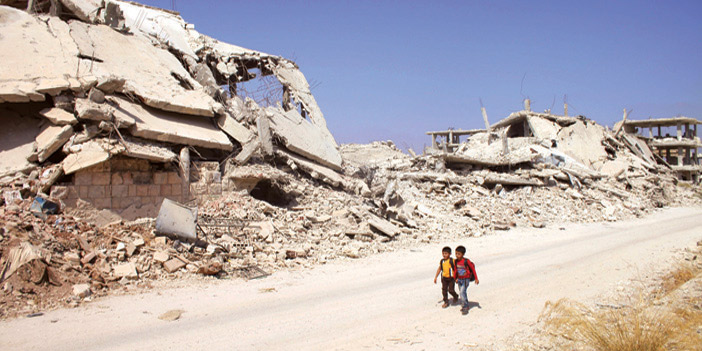  تلامذة سوريون في طريقهم إلى المدرسة وسط بنايات مدمرة في مدينة داريا