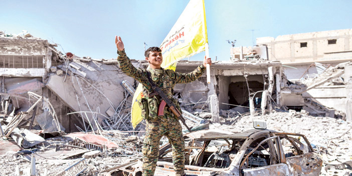  جندي من سوريا الديمقراطية يرفع علم قواته فرحاً بتحرير الرقة من تنظيم داعش