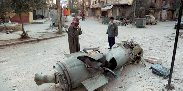   شابان يقفان عند إحدى القذائف التي أسقطها النظام وانفجرت في الغوطة
