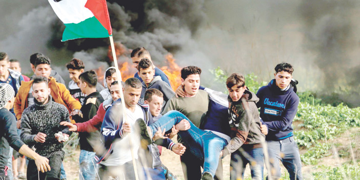   فلسطينيون يحملون زميلهم المصاب في أثناء احتجاجاتهم الغاضبة تجاه الاحتلال