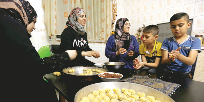  إحدى الأسر السورية تصنع حلويات العيد