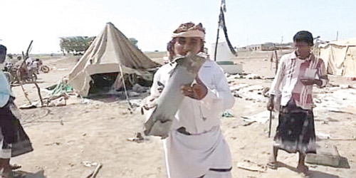  نازح يمني يحمل مقذوفاً حوثياً سقط على أحد مخيمات النازحين