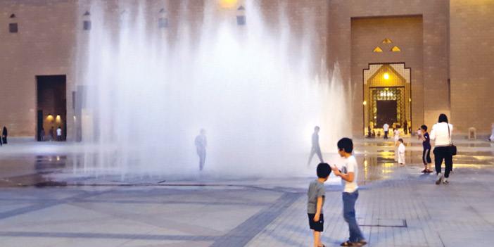  أطفال يلهون أمام نافورة المياه الواقعة في منطقة قصر الحكم وسط العاصمة الرياض