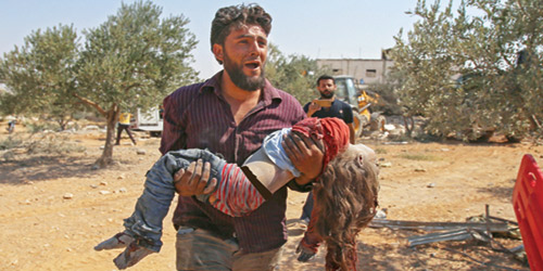  سوري يبكي وهو يحمل جثة طفلة صغيرة قتلت جراء قصف قوات الأسد