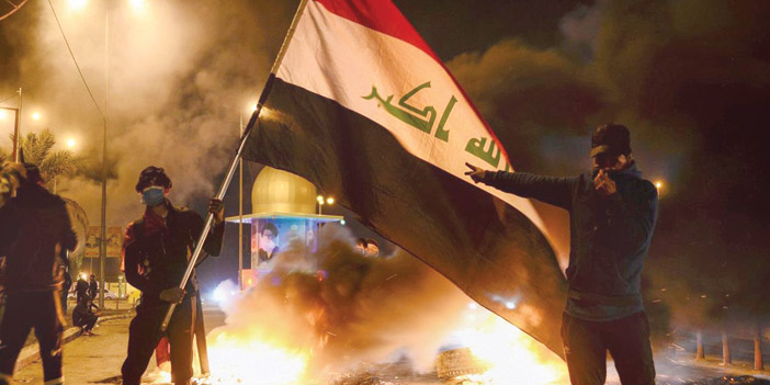  عراقيون يرفعون العَلَم الوطني خلال مظاهرات رفض علاوي