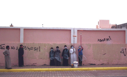 منسوبو مدرسة المهاجرين يطمسون الكتابات على جدران المدرسة 