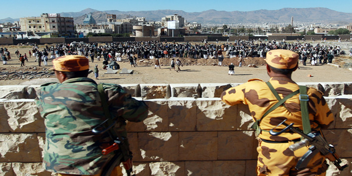  جنديان يمنيان يراقبان بينما يتم تشييع ضحايا انفجار كلية الشرطة