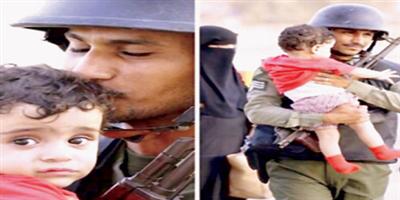 وكيل رقيب جوازات يقبِّل طفلاً يمنياً في مشهد إنساني 