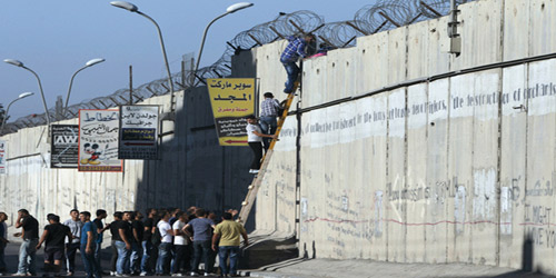  شبان فلسطينيون يحاولون اجتياز جدار الفصل لأداء الجمعة في الأقصى
