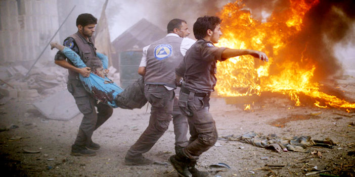  مسعفون يحملون مصابين بعد قصف طائرات النظام
