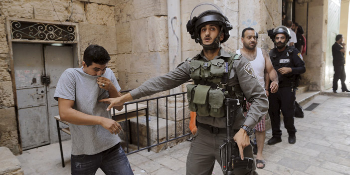  جندي إسرائيلي يمسك شاباً فلسطينياً بالقرب من المسجد الأقصى