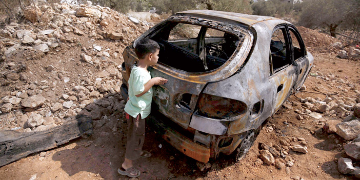  طفل ينظر إلى سيارة أبيه التي أشعل المحتلون النار بها بنابلس
