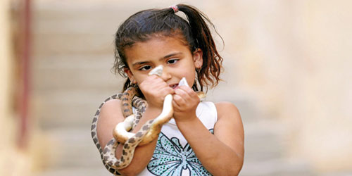 طفلة تضع ثعباناً على كتفيها 