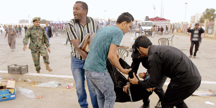  ليبيون يَحْملونَ امرأةً مصابة بعد القصف على مظاهرة ببنغازي
