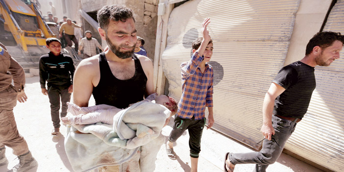  رجل يحمل طفلاً مقتولاً جراء قصف النظام هلى معرة النعمان