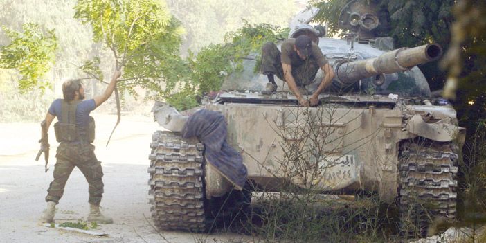 مقاتلو المعارضة يحاولون إخفاء دبابة من القصف الجوي خلال المعارك في حلب