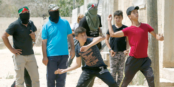  شبان فلسطينيون يقذفون الحجارة على قوات الاحتلال