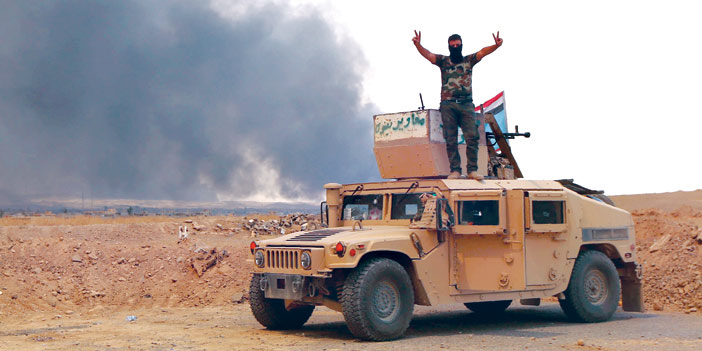  عنصر من الجيش العراقي يشير بعلامة الانتصار بعد السيطرة على القيارة