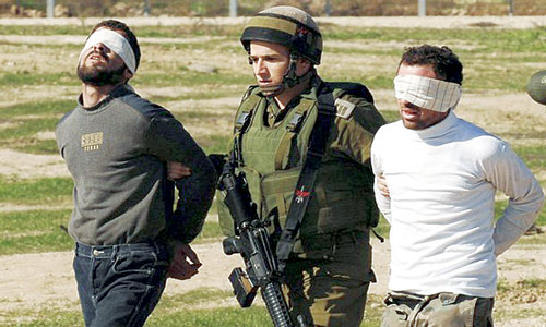   جندي صهيوني ممسكاً بشابين فلسطينيين في إطار حملة اعتقالات
