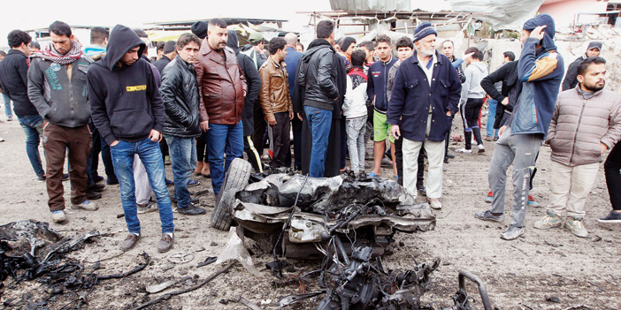  العراقيون يقفون على أجزاء سيارة متناثرة جراء الانفجار الانتحاري في بيجي