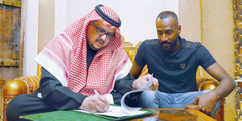  الأمير فيصل بن تركي أثناء توقيع العقد وبجانبه الحارس وليد عبدالله