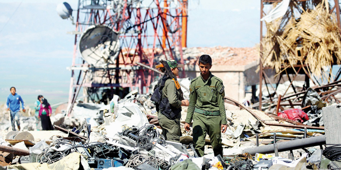 مقاتلون أكراد يتفقدون آثار القصف التركي لمركز الإعلام والإذاعة والاتصالات