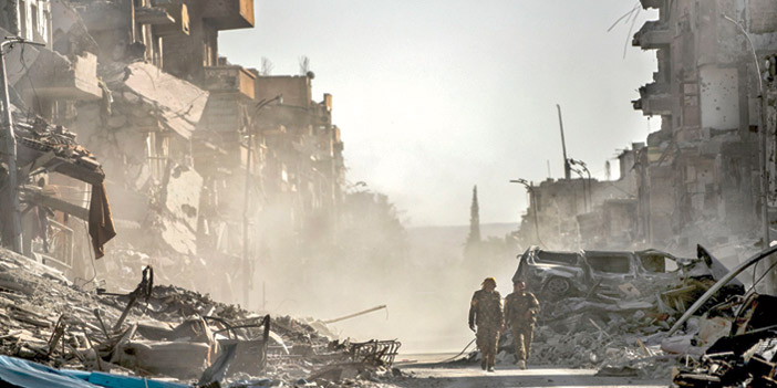  عناصر من قوات سوريا الديمقراطية يتجولون وسط الدمار في مدينة الرقة