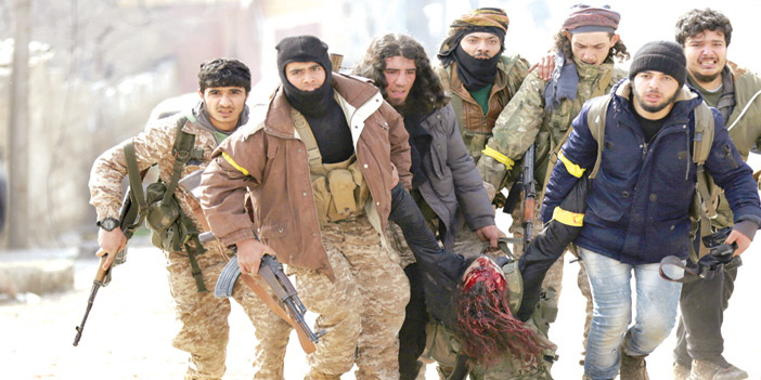  أفراد من الجيش السوري الحر يحملون زميلهم المصاب في مواجهات بعفرين