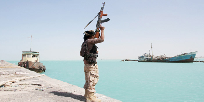  جندي من القوات الشرعية يرفع سلاحه في الميناء علامة على نصر قوات بلاده الشرعية
