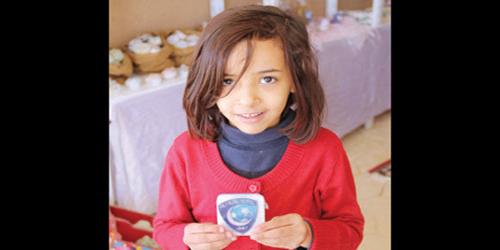  طفلة تحمل أحد المنتجات بشعار الزعيم