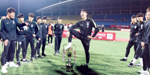  أحد لاعبي المنتخب الكوري يضع قدمه على الكأس
