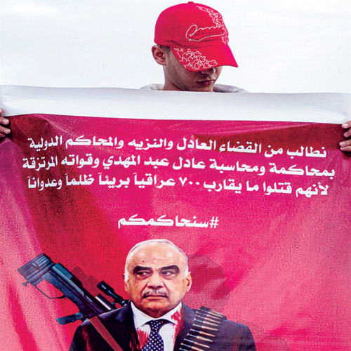  عراقي يحمل لافتة تطالب بمحاكمة عبدالمهدي والأجهزة الأمنية