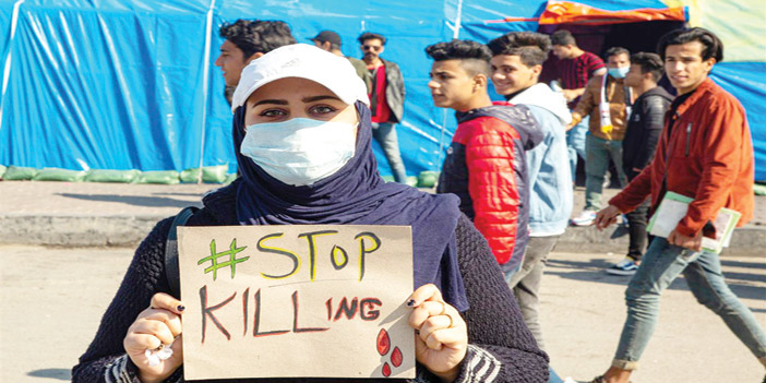  عراقية ترفع لافتة تطالب بوقف القتل بحق المتظاهرين