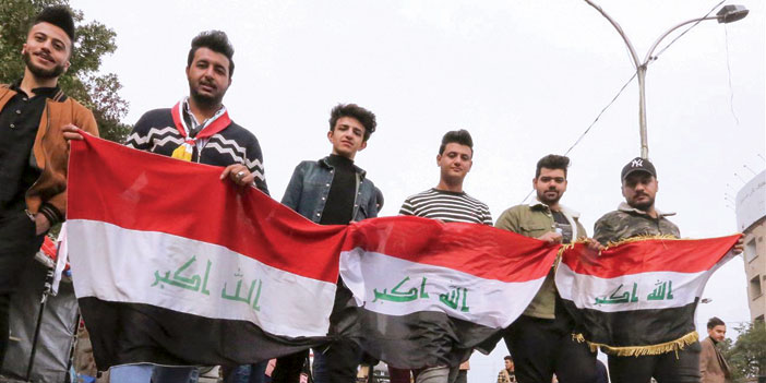  متظاهرون يحملون العلم العراقي في وجه قوات الأمن