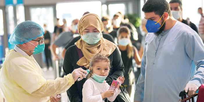  أحد الصحيين يدقق في درجات الحرارة للمسافرين في مطار دبي