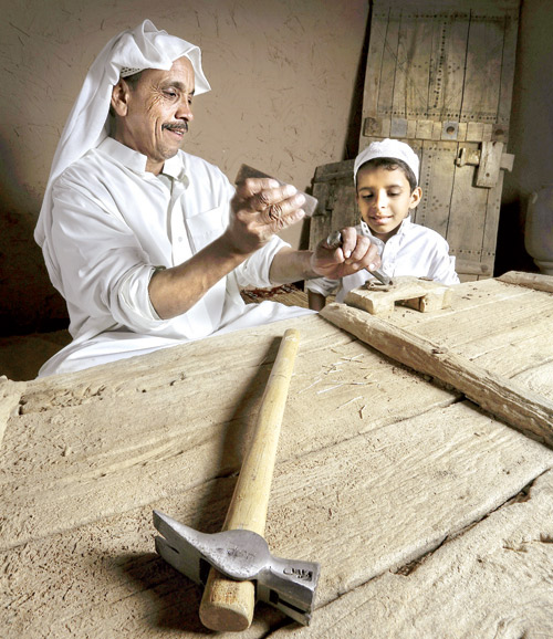  مهني يعلم ابنه حرفة صناعة الأبواب الخشبية التراثية