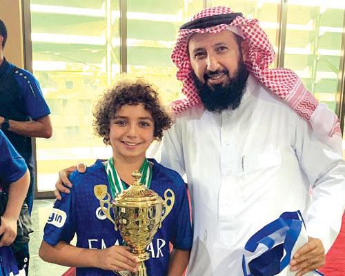  المقرن يحتفل مع أحد لاعبي فريق السباحة للبراعم